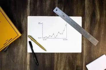 Papel com gráfico sobre a mesa simbolizando um planejamento para reduzir custos de uma empresa